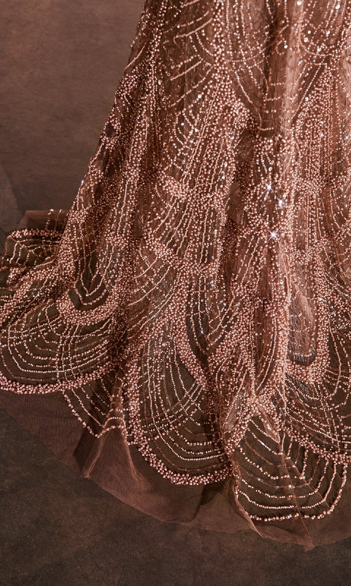 Close-up of the Ladivine CC4020: a Long Beaded Sienna Prom Dress featuring sheer fabric and intricate geometric beadwork, displayed against a dark background.